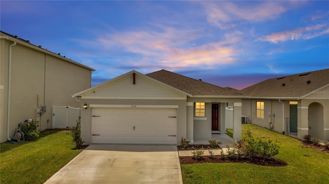 ranch-style house featuring a lawn, a garage, and central air condition unit