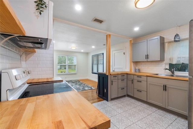 kitchen featuring tasteful backsplash, gray cabinets, electric range, sink, and butcher block counters