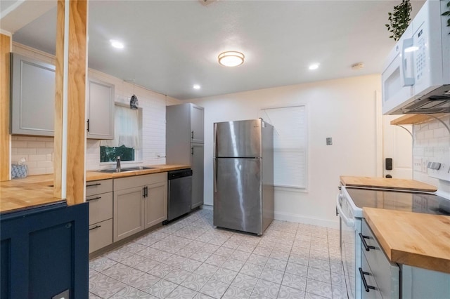 kitchen with decorative backsplash, sink, gray cabinetry, stainless steel appliances, and butcher block counters