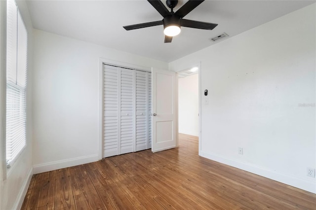 unfurnished bedroom with ceiling fan, wood-type flooring, and a closet