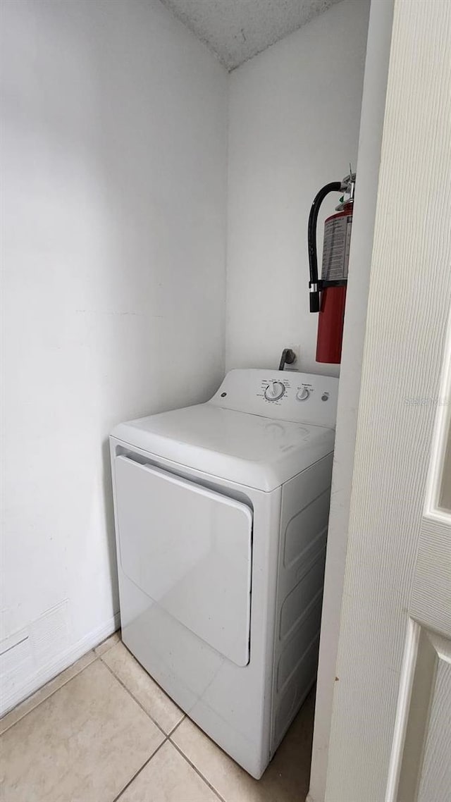 laundry room with light tile patterned flooring, a textured ceiling, and washer / dryer