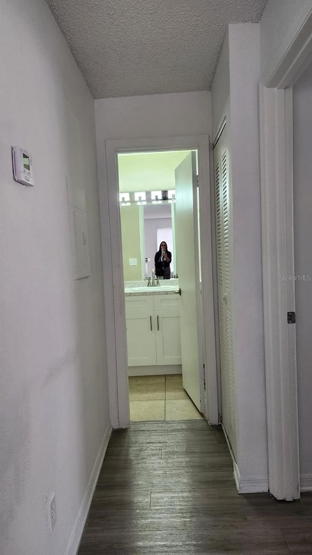 corridor featuring hardwood / wood-style flooring, sink, and a textured ceiling