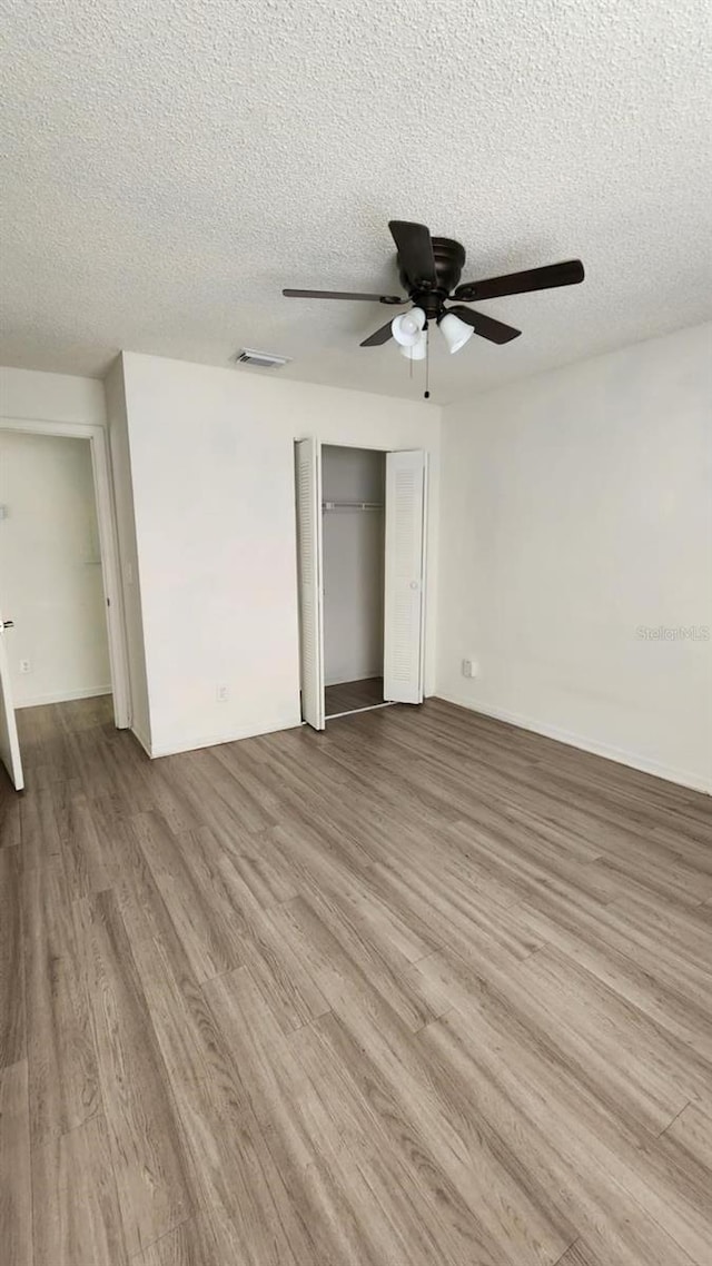 empty room featuring ceiling fan, a textured ceiling, and light hardwood / wood-style flooring