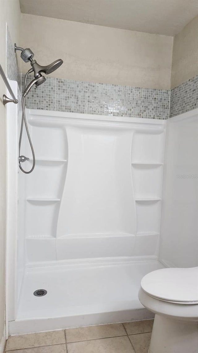 bathroom featuring a shower, tile patterned flooring, and toilet