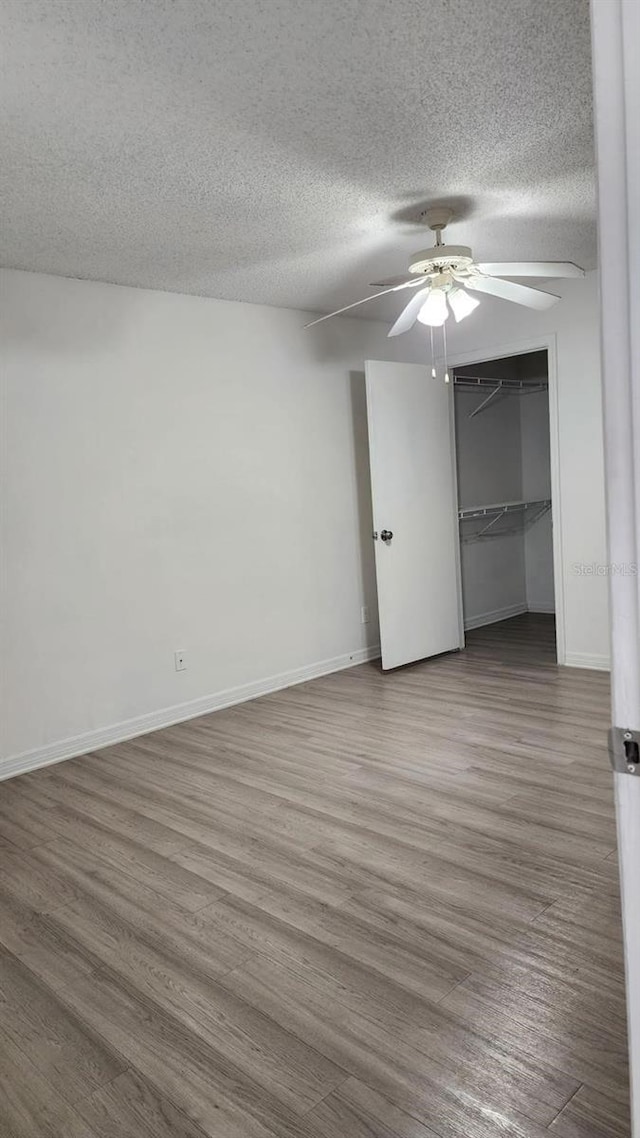 unfurnished room featuring hardwood / wood-style floors, ceiling fan, and a textured ceiling