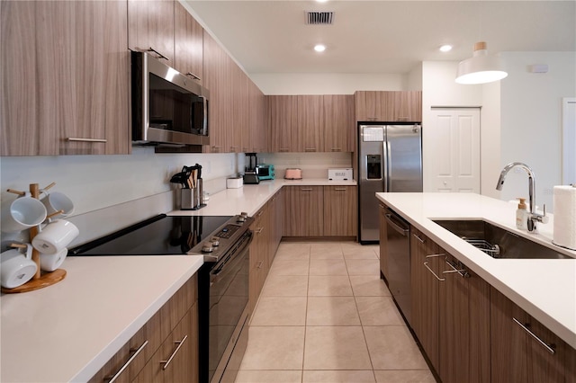 kitchen featuring decorative light fixtures, light tile patterned floors, sink, and appliances with stainless steel finishes