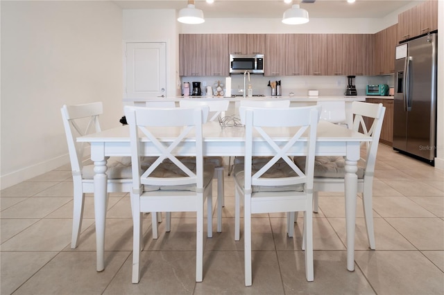 kitchen featuring decorative light fixtures, light tile patterned floors, stainless steel appliances, and a breakfast bar