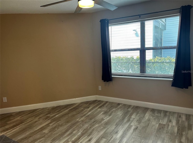 spare room featuring ceiling fan, a healthy amount of sunlight, and hardwood / wood-style flooring