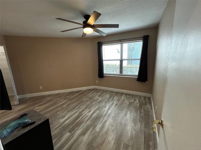 spare room with ceiling fan, a textured ceiling, and light hardwood / wood-style flooring