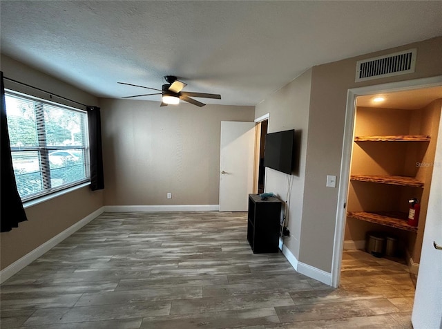 unfurnished living room with ceiling fan, hardwood / wood-style floors, and a textured ceiling