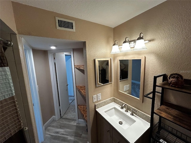 bathroom featuring vanity, wood-type flooring, and a textured ceiling