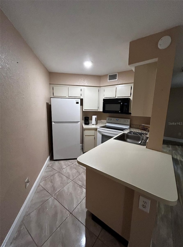 kitchen with sink, white appliances, kitchen peninsula, and light tile patterned floors