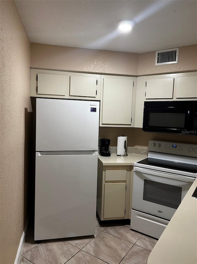 3984 Atrium Dr Unit 4, Orlando, FL 32822 - kitchen with electric range, visible vents, freestanding refrigerator, black microwave, and light countertops
