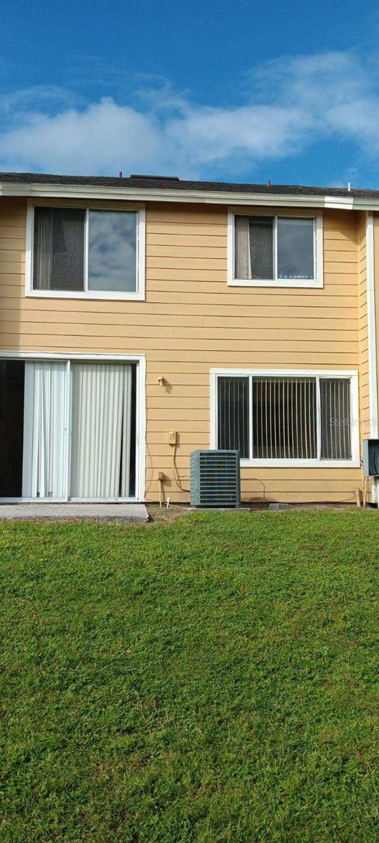 rear view of house with central air condition unit and a yard