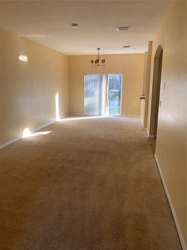 spare room with carpet flooring and a chandelier