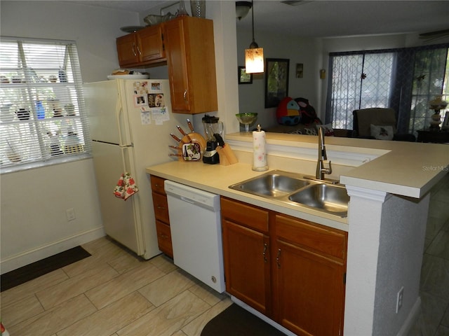 kitchen featuring kitchen peninsula, white appliances, decorative light fixtures, and sink