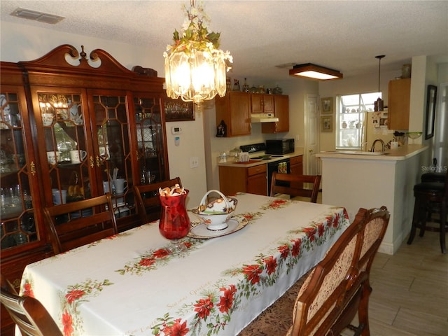 dining space with a textured ceiling and an inviting chandelier