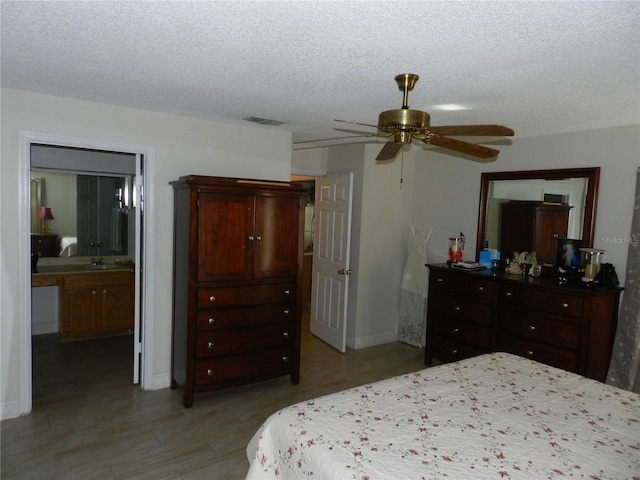 bedroom featuring ceiling fan, a textured ceiling, and connected bathroom