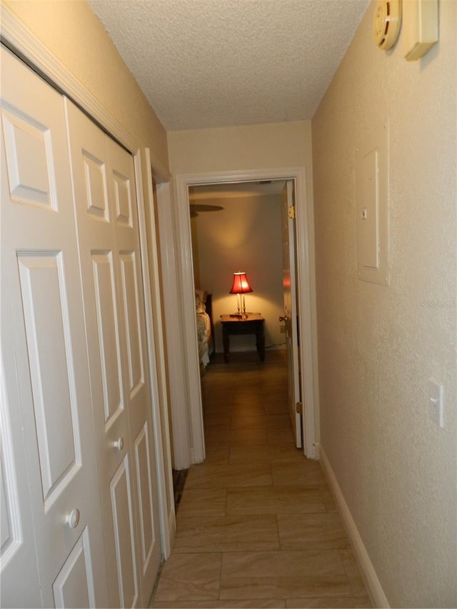 hall featuring electric panel, a textured ceiling, and light wood-type flooring