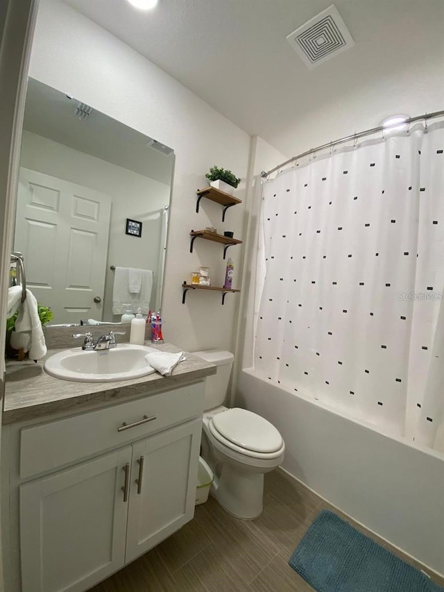 full bathroom with hardwood / wood-style floors, vanity, shower / tub combo, and toilet