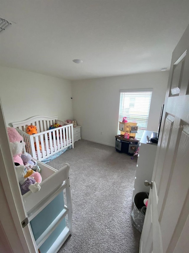 bedroom featuring carpet and a nursery area