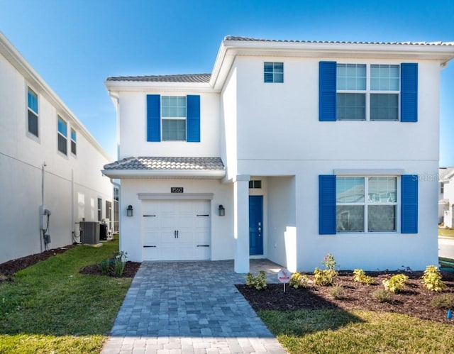 view of front of home with a front lawn, central AC unit, and a garage