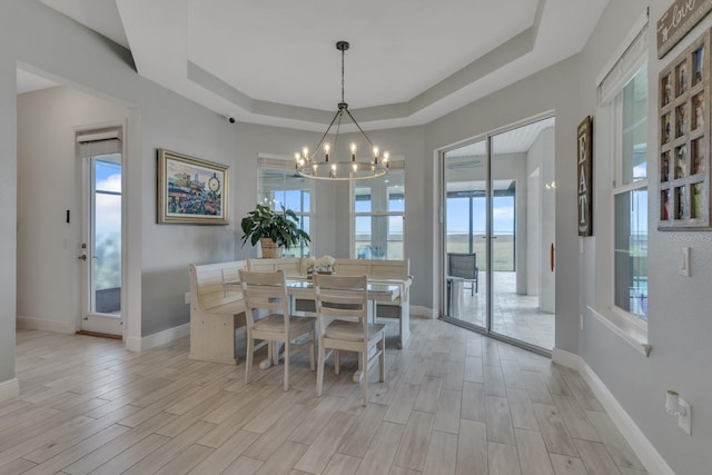 dining area with a tray ceiling, an inviting chandelier, and a wealth of natural light