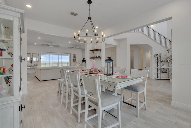 dining area with light hardwood / wood-style flooring and ceiling fan with notable chandelier