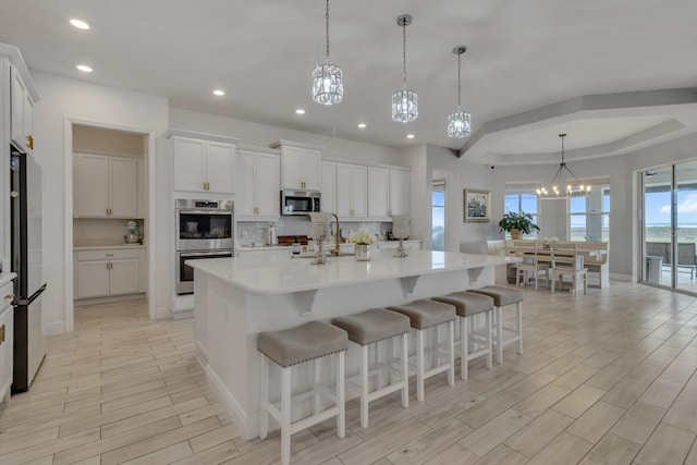 kitchen featuring stainless steel appliances, a spacious island, an inviting chandelier, white cabinets, and hanging light fixtures