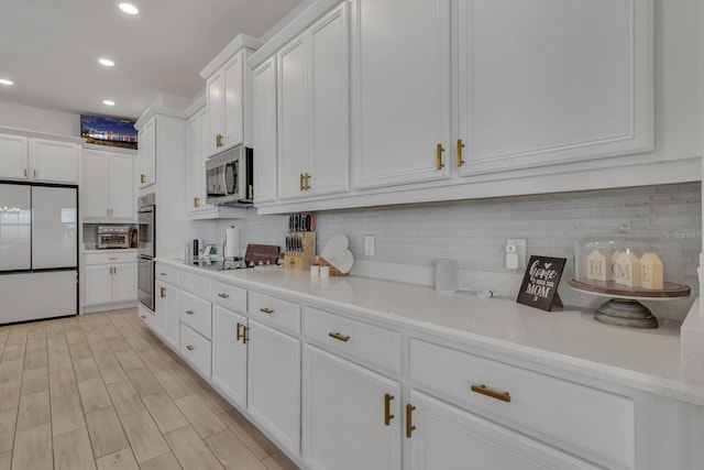 kitchen featuring tasteful backsplash, white cabinetry, light hardwood / wood-style flooring, and appliances with stainless steel finishes