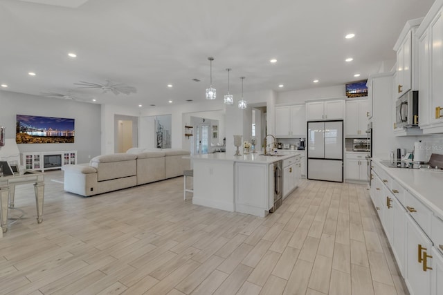 kitchen featuring a center island with sink, white fridge, white cabinets, and sink