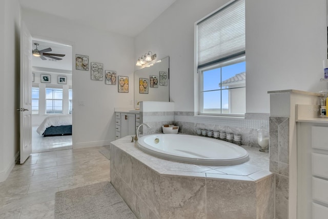 bathroom with vanity, ceiling fan, and tiled tub