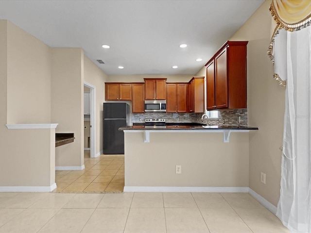 kitchen with appliances with stainless steel finishes, a kitchen breakfast bar, kitchen peninsula, and backsplash