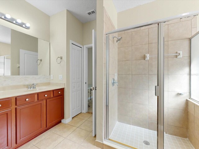 bathroom featuring tile patterned floors, a shower with shower door, and vanity