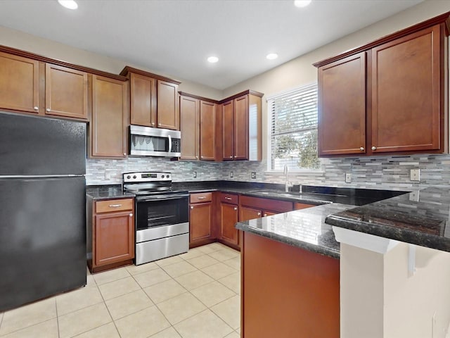 kitchen with light tile patterned floors, stainless steel appliances, sink, and dark stone counters