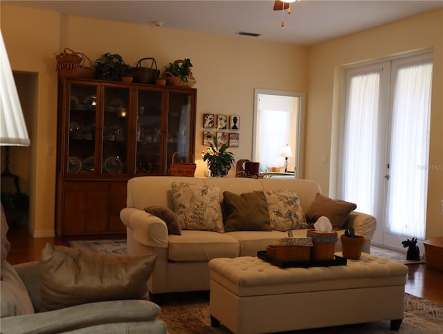 living room featuring ceiling fan, wood-type flooring, and a wealth of natural light