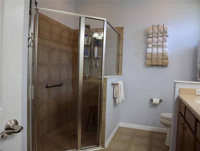 bathroom with a shower with shower door, toilet, vanity, and tile patterned flooring