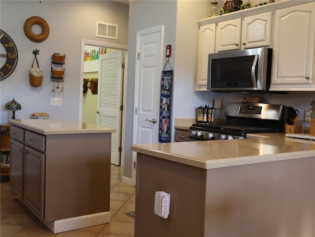 kitchen with a kitchen island, white cabinetry, gray cabinetry, stainless steel appliances, and light tile patterned floors