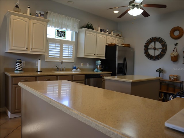 kitchen featuring light tile patterned floors, ceiling fan, appliances with stainless steel finishes, a kitchen island, and sink