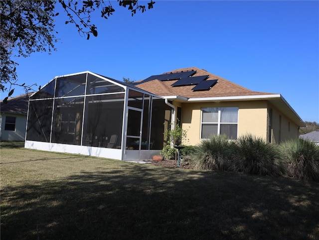 rear view of property with a lawn and solar panels