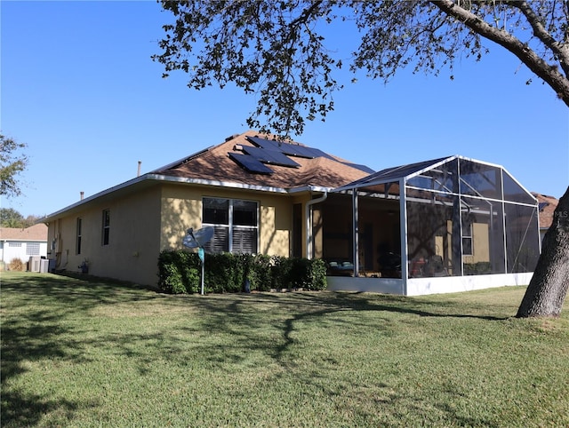 rear view of house with a lawn and solar panels