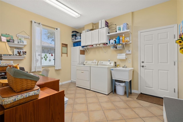 laundry area with light tile patterned floors, washer and clothes dryer, cabinet space, and baseboards