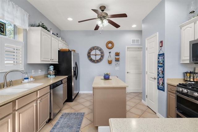 kitchen featuring light tile patterned floors, a kitchen island, appliances with stainless steel finishes, light countertops, and a sink