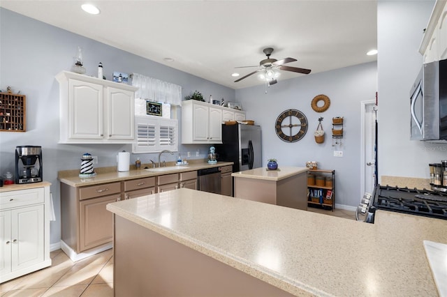 kitchen with stainless steel appliances, a ceiling fan, white cabinets, a kitchen island, and a sink