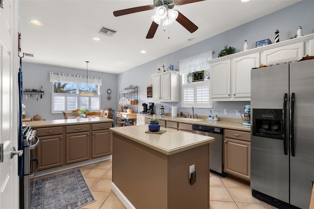 kitchen with appliances with stainless steel finishes, light countertops, a sink, and light tile patterned flooring