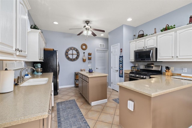 kitchen featuring visible vents, appliances with stainless steel finishes, a center island, white cabinetry, and a sink