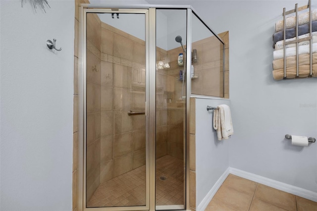 bathroom with baseboards, a shower stall, and tile patterned floors