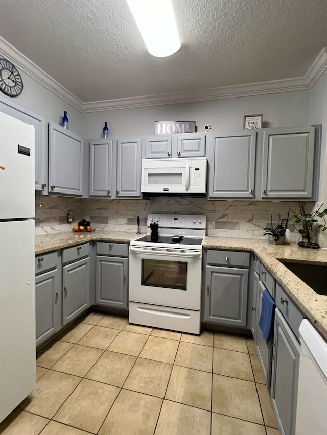 kitchen featuring gray cabinets, light tile patterned floors, white appliances, and ornamental molding