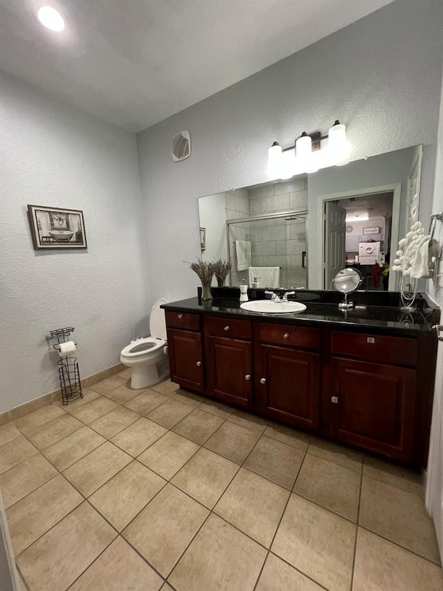 bathroom featuring toilet, vanity, tile patterned floors, and walk in shower