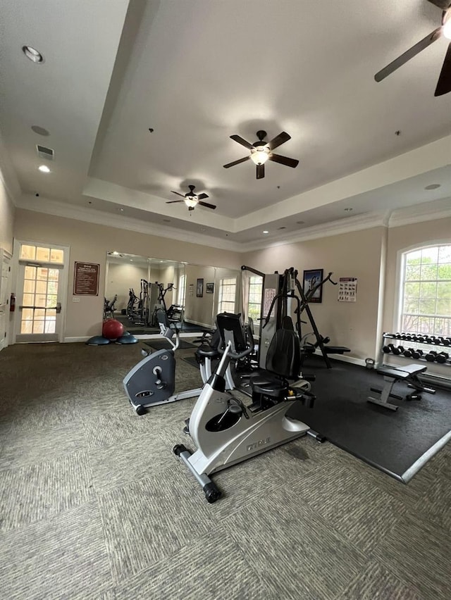 exercise room with ceiling fan, a raised ceiling, and crown molding